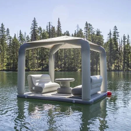 Group relaxing on the Backside Lounge, a spacious inflatable lounge, floating near a yacht in a lake setting