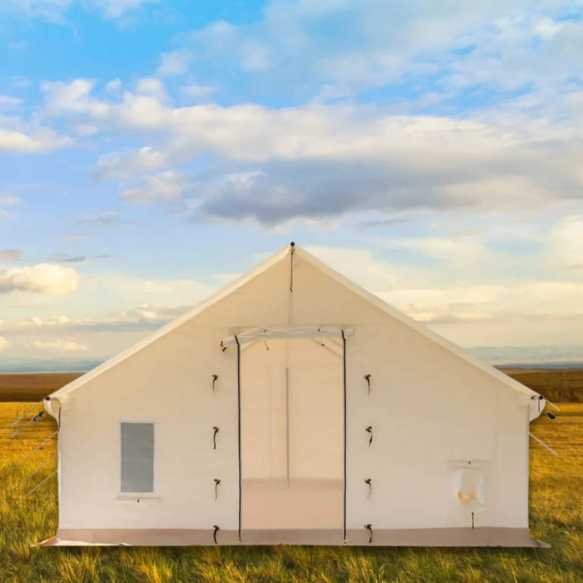 Beige camping tent in a grassy field with a blue sky and clouds