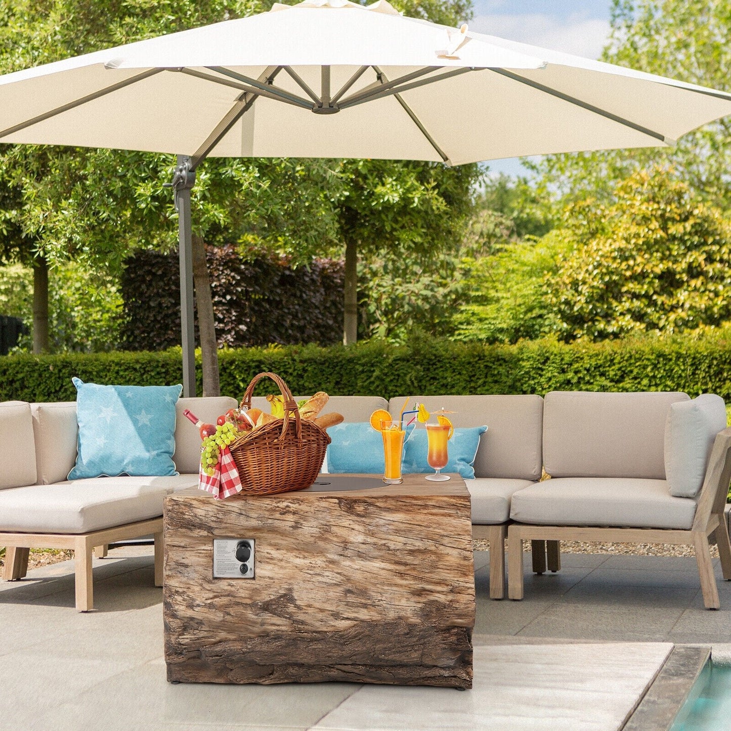 Outdoor patio setting with beige sofa, wooden coffee table, and large umbrella in a garden.