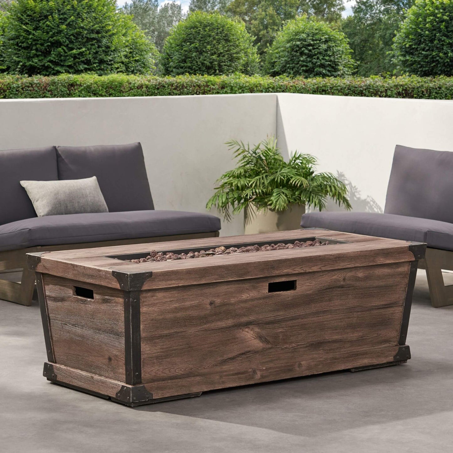 Wooden fire pit table on a patio with outdoor furniture and plants.