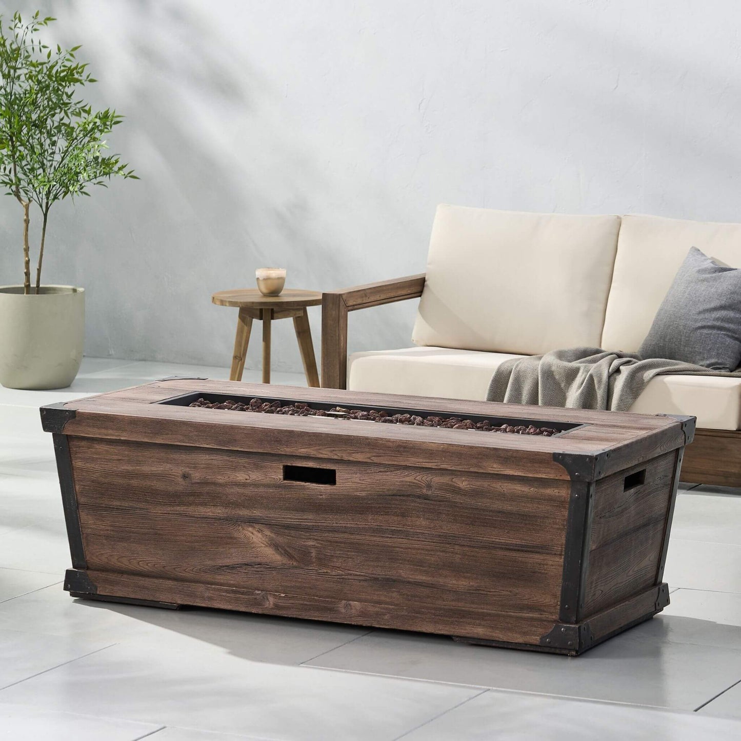 Wooden fire pit table in a living room setting with a couch and side table.