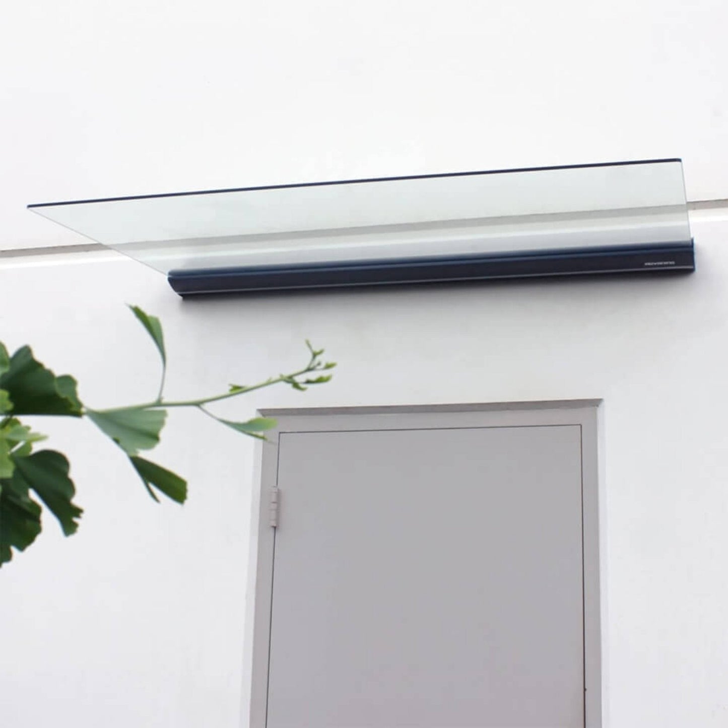Roll-up solar window blind on a white door with a plant in the foreground