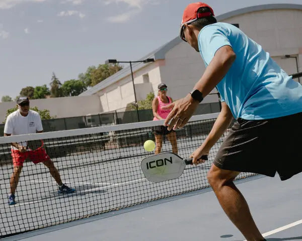 Players enjoying an intense pickleball game on a sunny day, showcasing paddles and balls in action