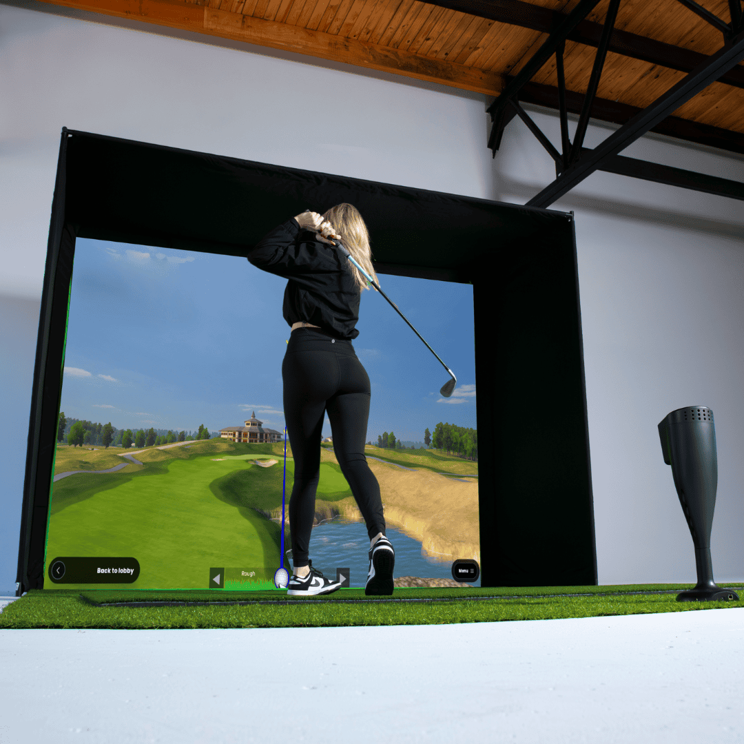 Red Stakes Golf simulator setup with hitting mat and projector.