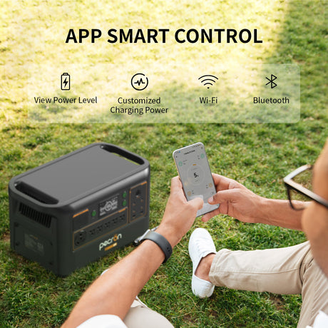 Person using a smartphone app to control an outdoor power station on grass