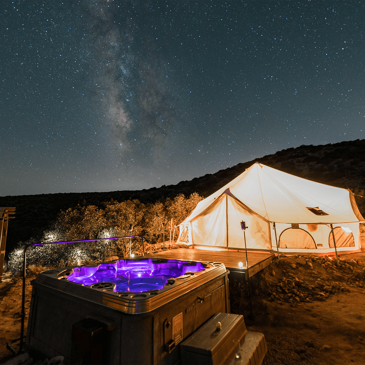 Tent and hot tub under a starry night sky with the Milky Way visible.