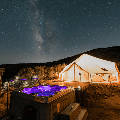 Tent and hot tub under a starry night sky with the Milky Way visible.