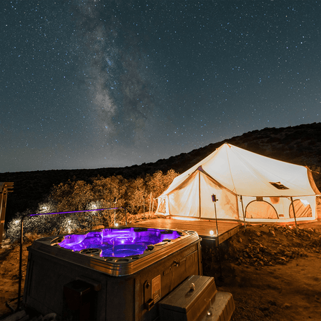 Tent and hot tub under a starry night sky with the Milky Way visible.