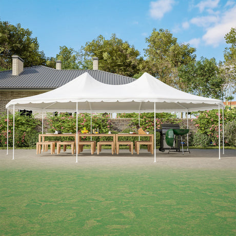 White outdoor canopy tent set up on a grassy area with a house and trees in the background.