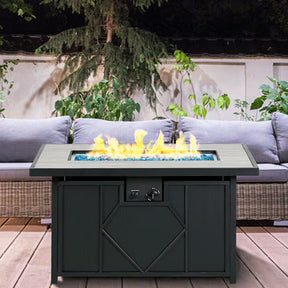 Outdoor fire pit table with flames on a patio with a couch and plants in the background
