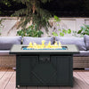 Outdoor fire pit table with flames on a patio with a couch and plants in the background