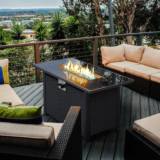 Outdoor patio setup with fire pit table, chairs, and cushions on a deck with scenic view.
