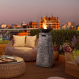 Outdoor patio with wicker furniture, fire pit, and city skyline view.