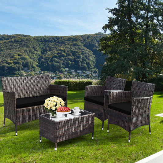 Outdoor patio set with chairs, table, and flowers on a grassy area with trees and mountains in the background.
