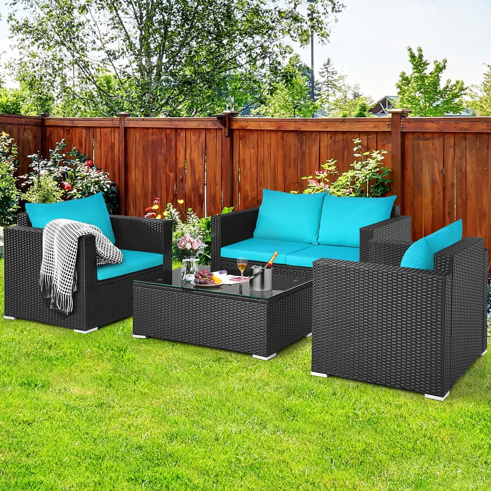 Outdoor patio set with black wicker furniture and blue cushions on a grassy area.