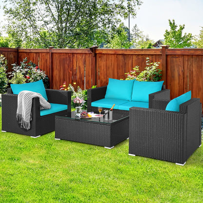 Outdoor patio set with black wicker furniture and blue cushions on a grassy area.