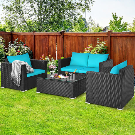 Outdoor patio set with black wicker furniture and blue cushions on a grassy area.