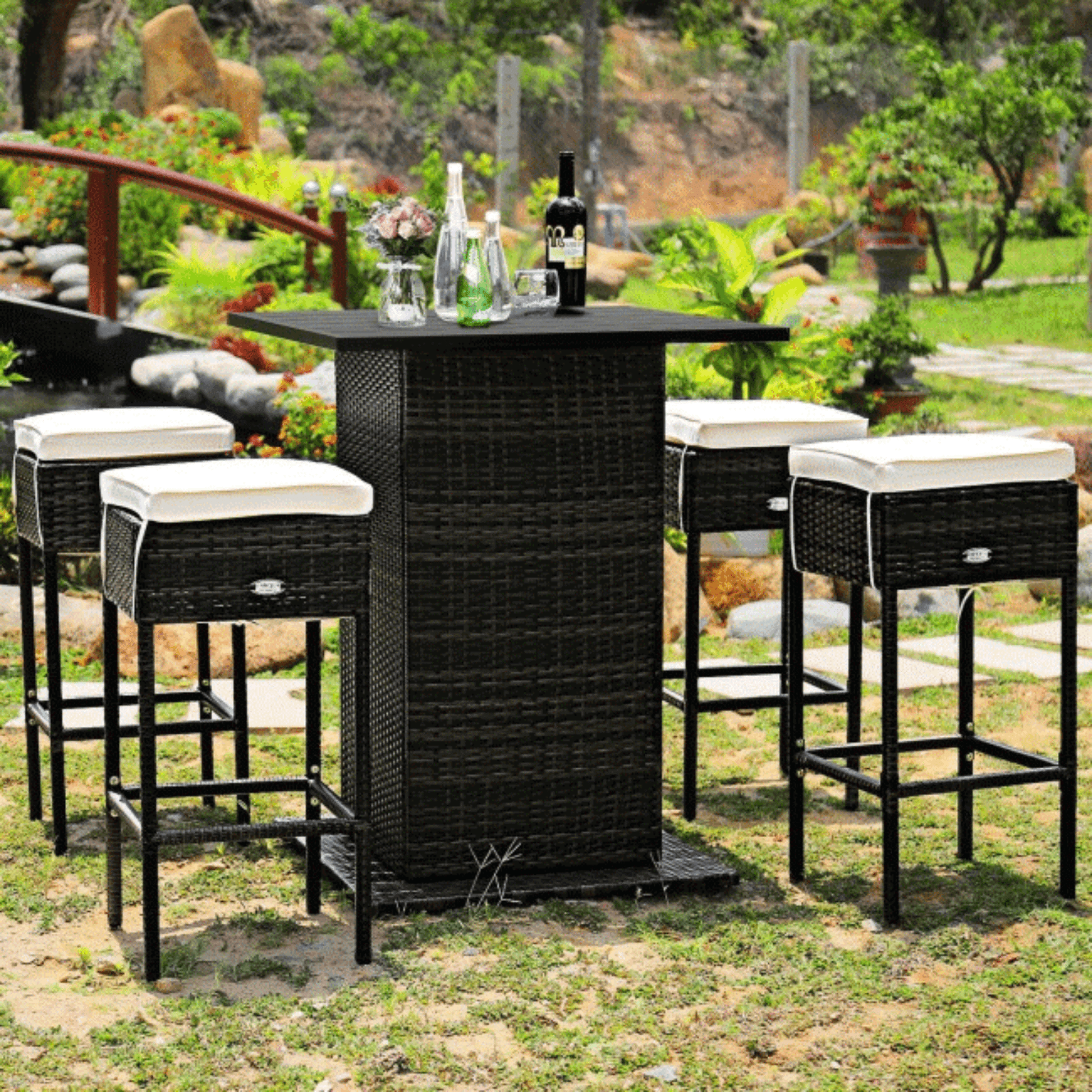 Outdoor patio set with black wicker bar and stools in a garden setting