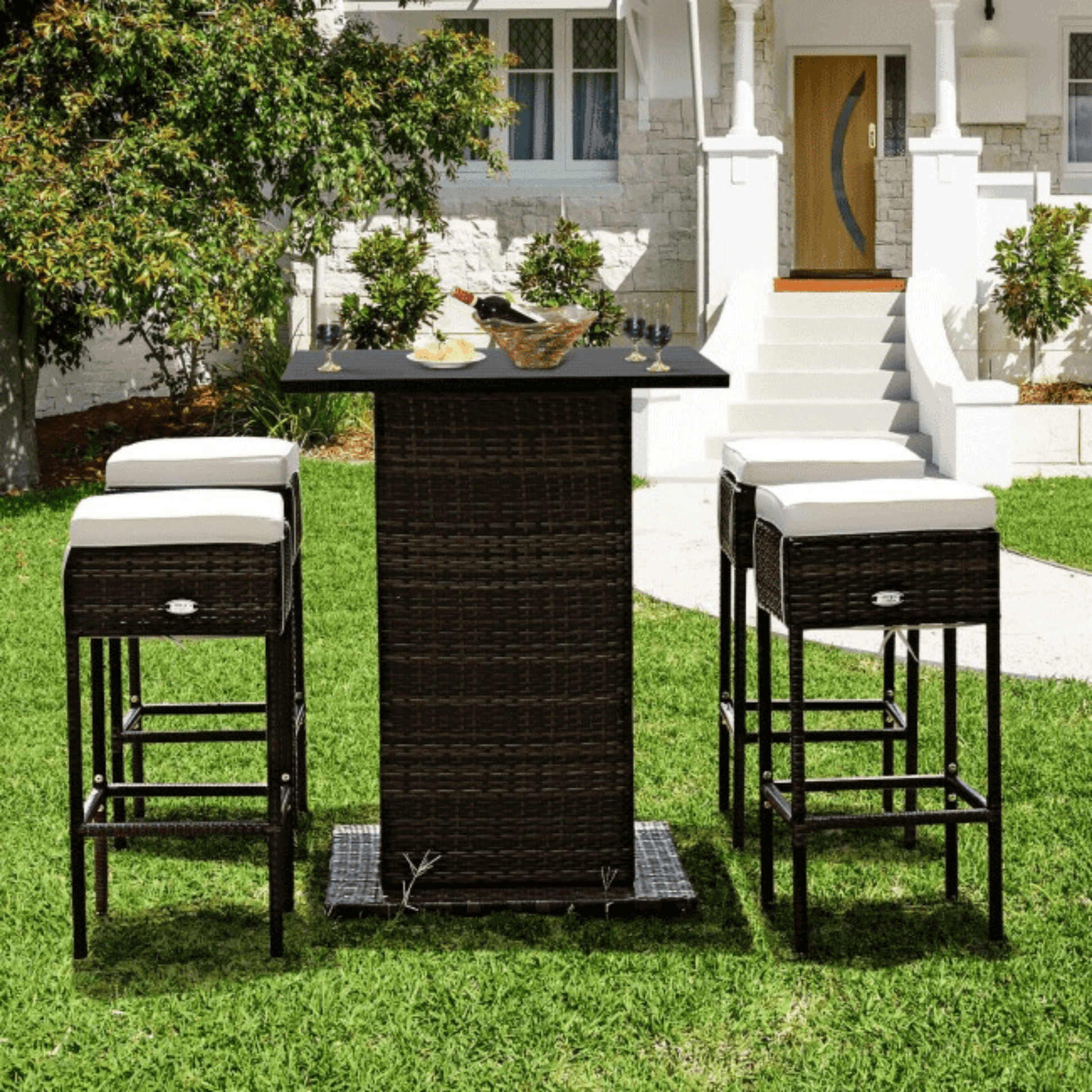 Outdoor patio set with black bar table and stools on a grassy lawn.