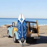 Blue and white surfboard with a wooden vehicle on a beach