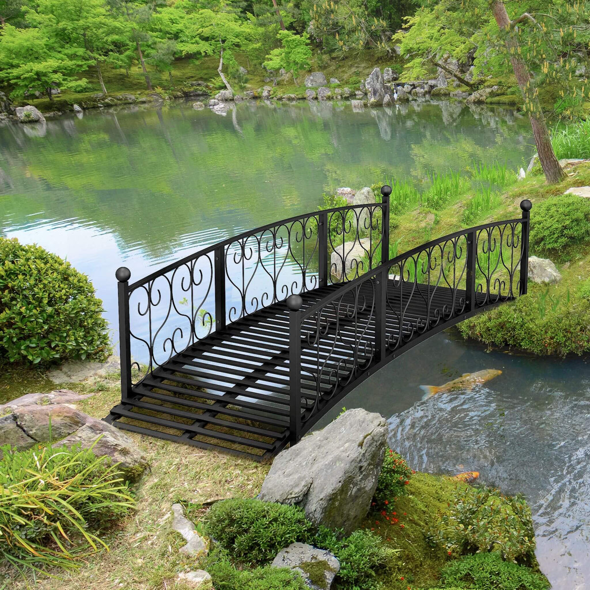 Black metal bridge over a pond in a lush green garden