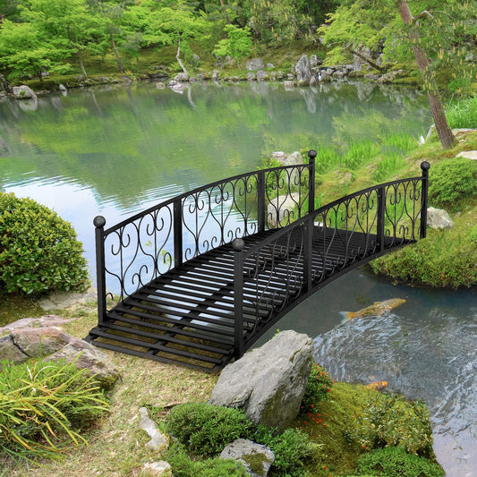 Black metal bridge over a pond in a lush green garden