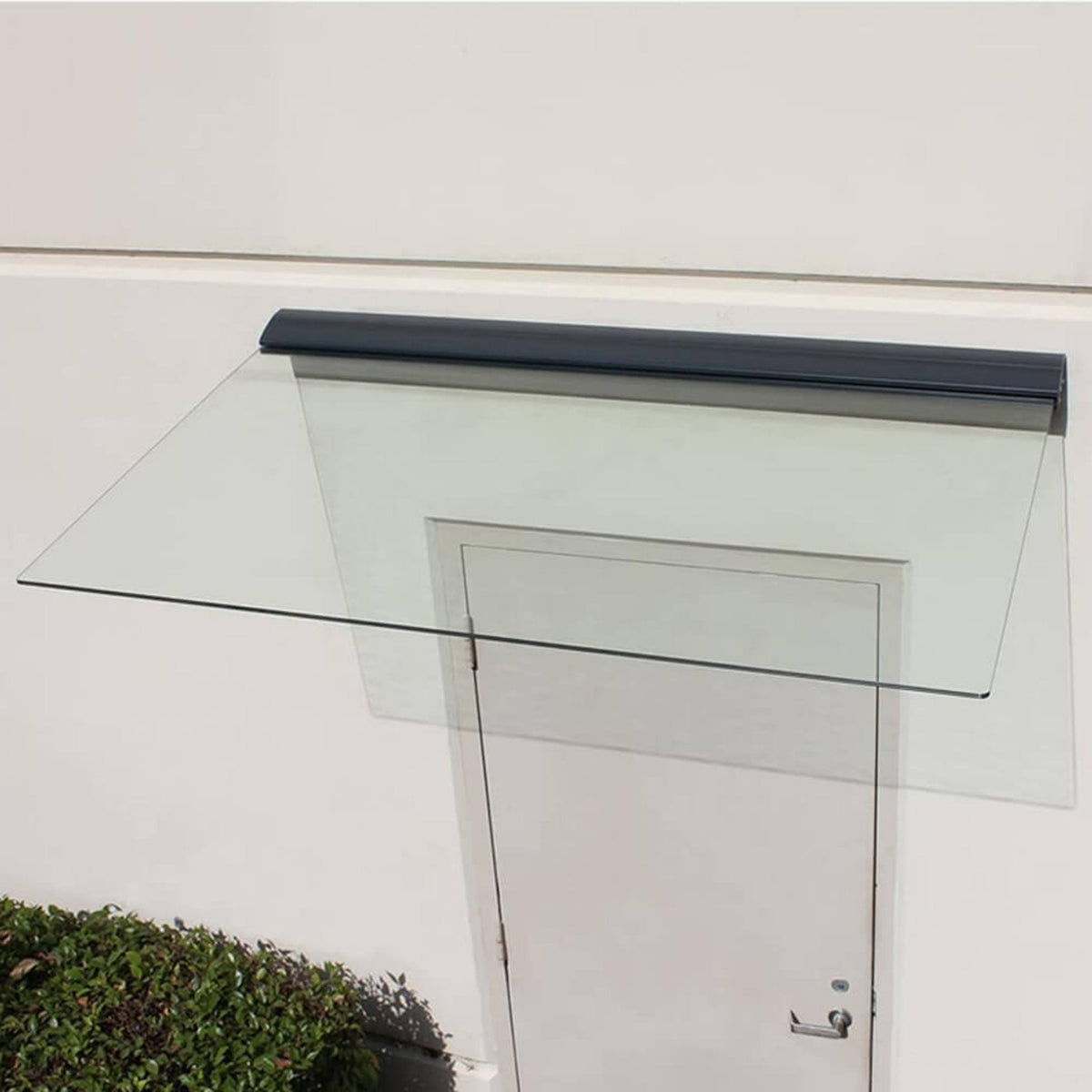 Glass door canopy with a white door and black trim on a light gray wall.