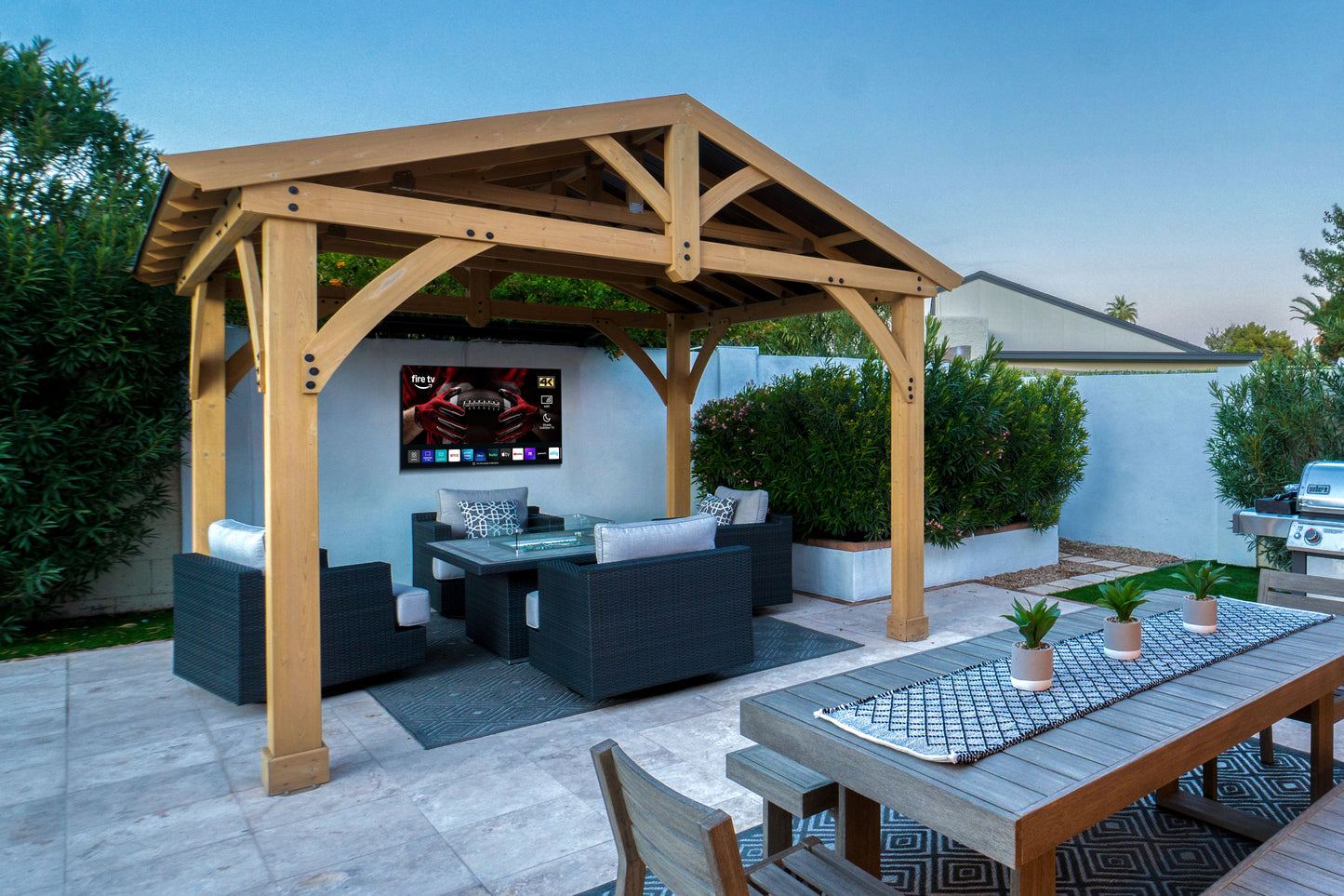 Wooden pergola with outdoor furniture and MirageVision Outdoor TV screen in a backyard setting