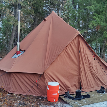 Brown tent with a chimney and orange cooler in a forest setting