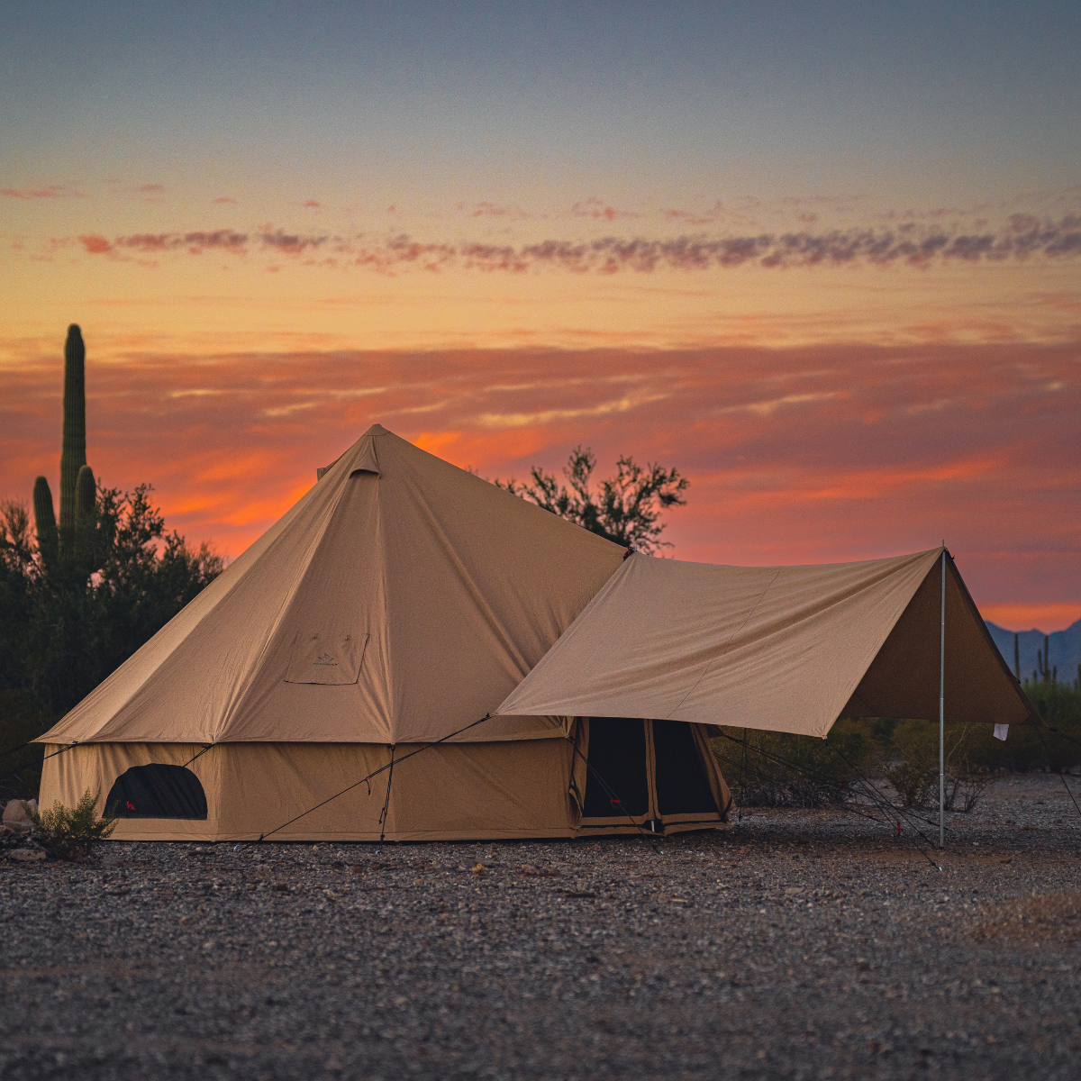 Beige camping tent in a desert landscape with a sunset sky