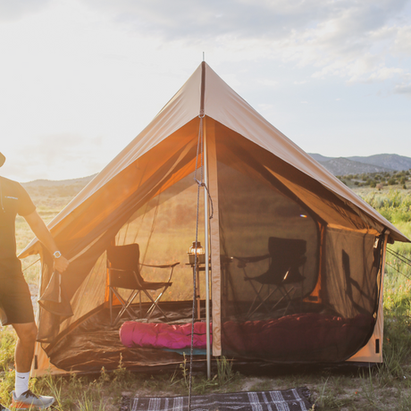 Camping tent with interior furniture in a natural setting