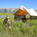 Person in a field of wildflowers with a tent in the background