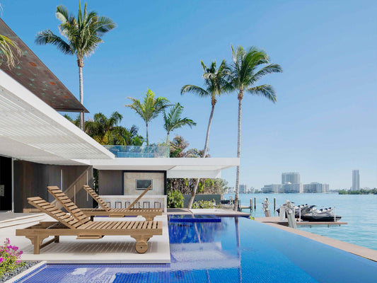 Luxury pool area with lounge chairs, palm trees, and waterfront view.