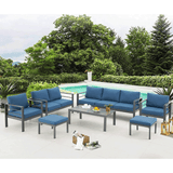 Outdoor patio set with blue cushions and a coffee table by a poolside.