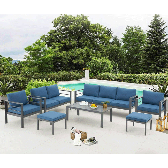 Outdoor patio set with blue cushions and a coffee table by a poolside.