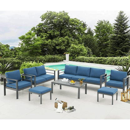 Outdoor patio set with blue cushions and a coffee table by a poolside.