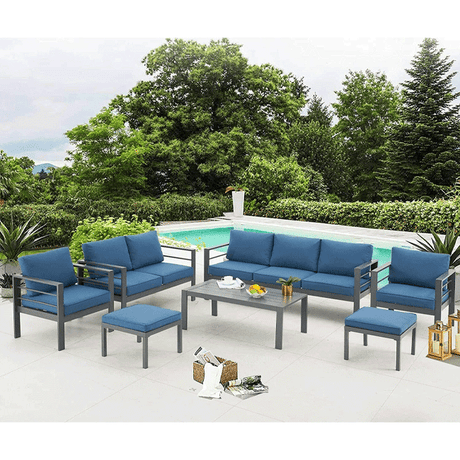 Outdoor patio set with blue cushions and a coffee table by a poolside.