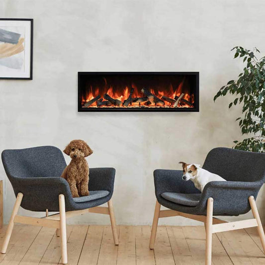 Two dogs sitting on gray chairs in front of a modern electric fireplace.