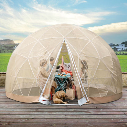 A large beige outdoor igloo garden greenhouse dome tent with a transparent TPU surface. It is set up on a wooden deck with plants inside and a dog lying on the floor.