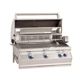 A built-in Fire Magic Aurora Multi-User Built-In Grill with analog thermometer and rotisserie kit, featuring stainless steel construction and blue control knobs, against an orange background.