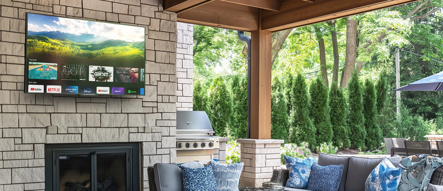 Outdoor living space with a Mirage Vision Gold Series 4K outdoor TV mounted on a stone wall, fireplace, and patio furniture.